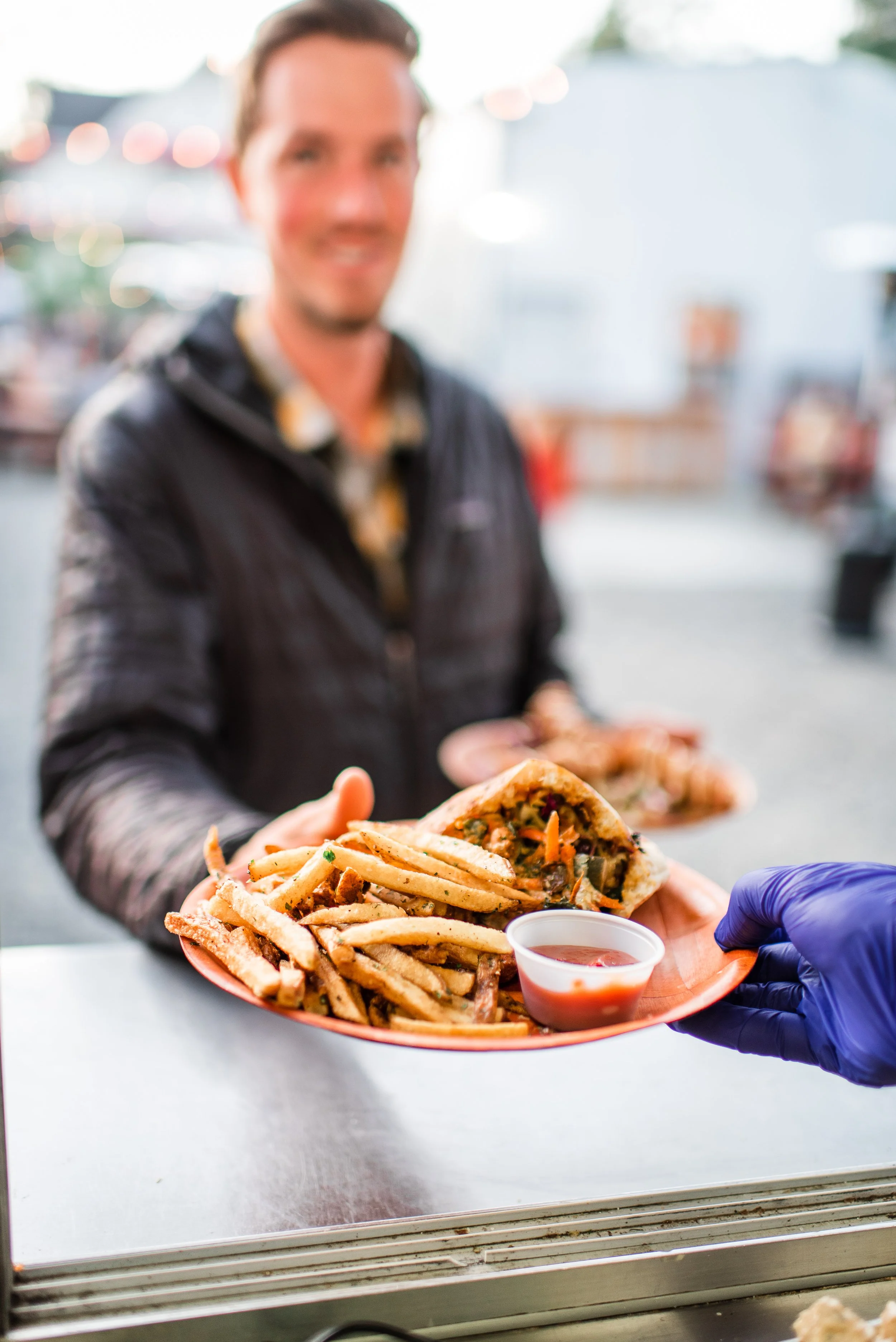 A plate of falafel and fries being handed through the food truck window