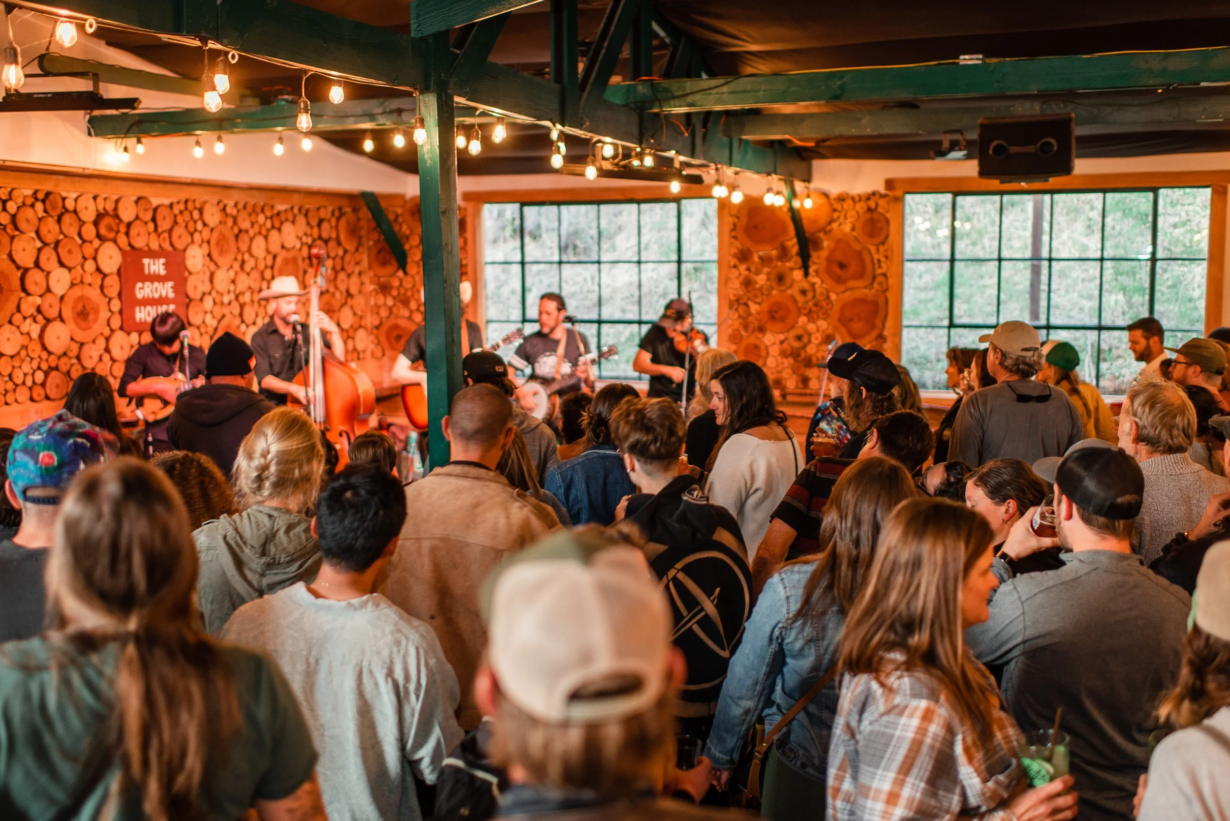 A packed crowd watching a band on the log-walled stage at The Grove House